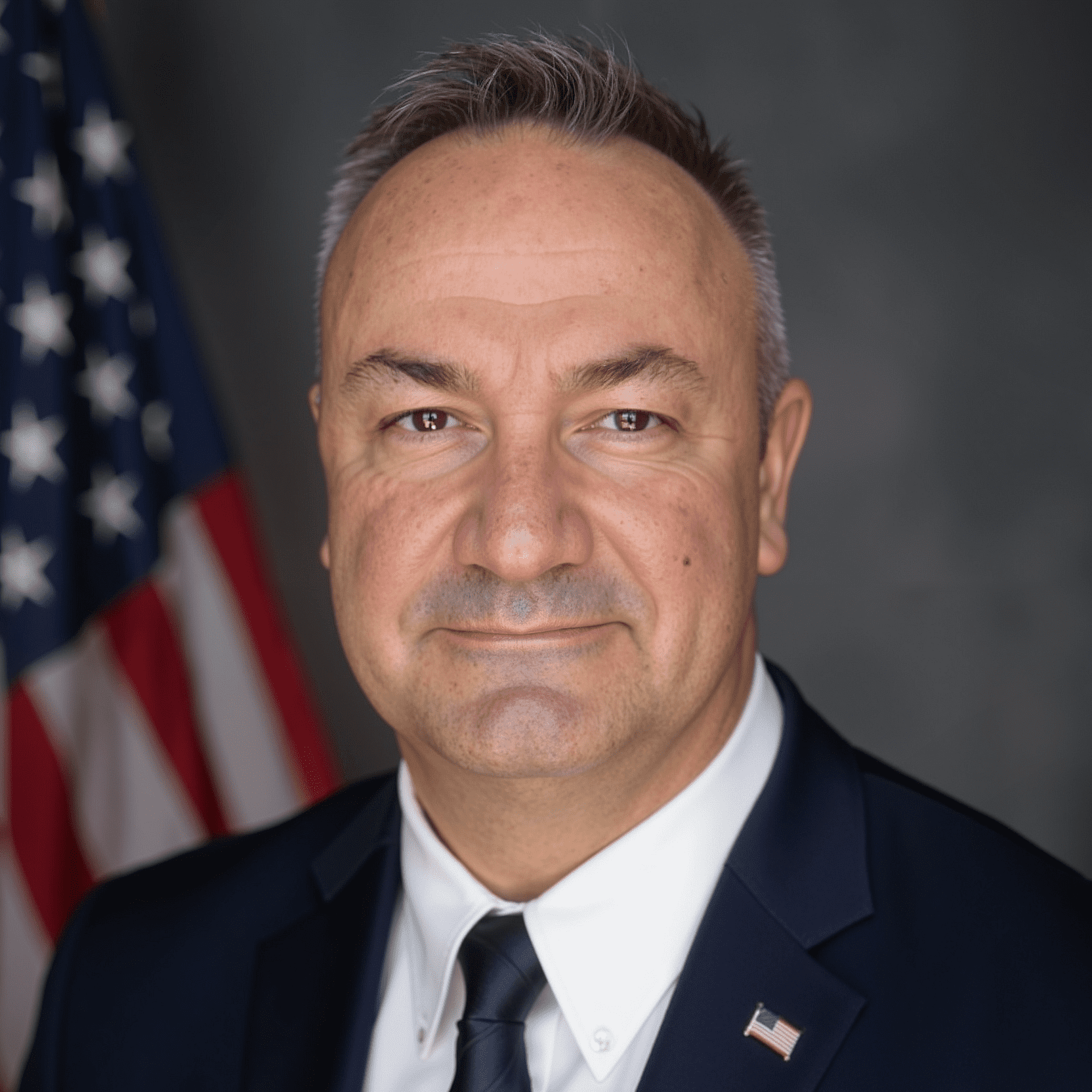 Man in suit with American flag background.